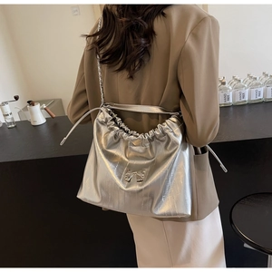 Dettaglio borsa tote con catena argento con design a pieghe e fiocco metallico sulla spalla