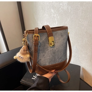 Detail van denim emmertas met lederen rand, metalen slot en schattige pluche pop