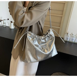 Borsa tote plissettata argento con catena metallica e dettaglio fiocco indossata