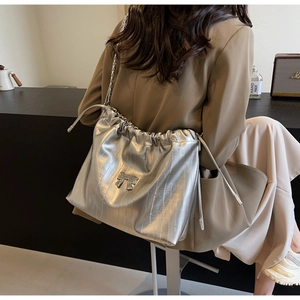 Dettaglio della borsa tote argento con coulisse e fiocco indossata da una modella