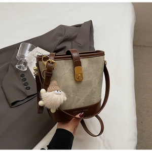 Detail van retro emmertas met bruine lederen bies, goudkleurig slot en pluche hanger