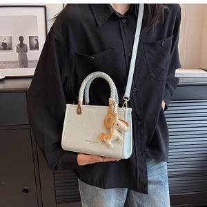 Detail view of mint green textured leather mini tote with woven handle and pony charm