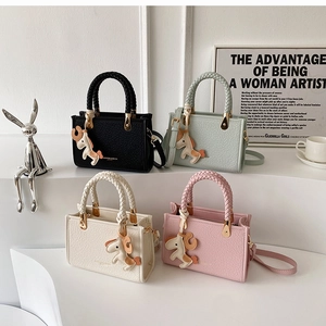 Detailed view of woven handles, litchi texture leather, and cute horse charms on tote bags
