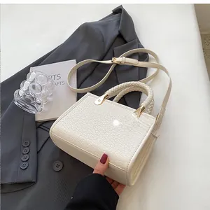 Detail of white embossed leather tote bag with woven handle and gold hardware