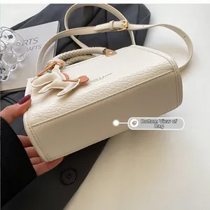Detailed bottom view of a white faux crocodile leather handbag with reinforced stitching