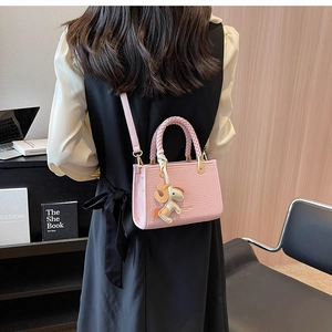 Pink croc-embossed handbag with woven handle and small horse charm on model