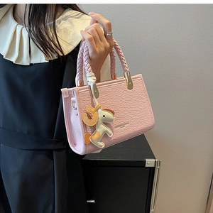 Pink tote bag with crocodile texture, woven handle and a horse charm detail