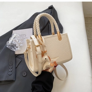 Detail of cream-colored crocodile embossed tote with woven handle and gold-tone accents