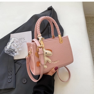 Pink embossed leather tote bag featuring woven handles and a cute animal charm