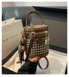 Detail of houndstooth cylinder bag with leather handles and a cute rabbit charm