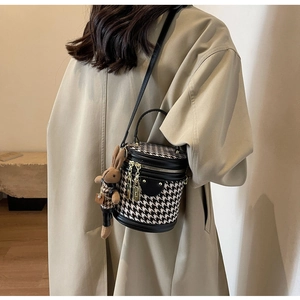 Detailed view of houndstooth bucket bag with leather trim and plush bunny charm
