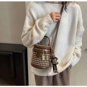 Detail of retro houndstooth bucket bag with leather handles and cute bunny charm accessory
