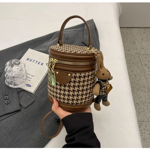 Detail of houndstooth bucket bag with golden hardware and cute bunny pendant charm