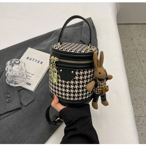 Detail of houndstooth bucket bag with leather trim and brown knit bunny charm