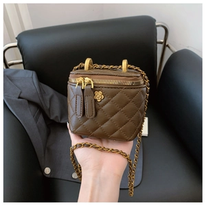 Dettaglio mini borsa a secchiello trapuntata marrone con charm camelia oro e catena