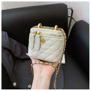 Dettaglio mini borsa trapuntata bianca con logo a fiore dorato e tracolla in pelle