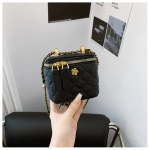 Dettaglio mini borsa a secchiello trapuntata nera con catena oro e decoro fiore camelia