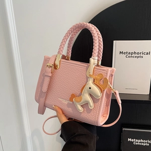 Pink lychee textured crossbody bag with woven handle and a decorative horse charm