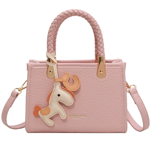 Pink faux leather tote bag with woven handles and horse charm on white background