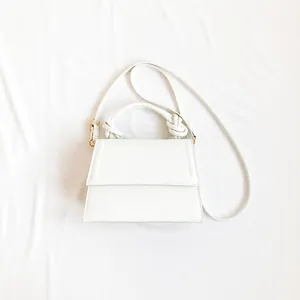 White trapezoid handbag with top handle and phone for size comparison reference