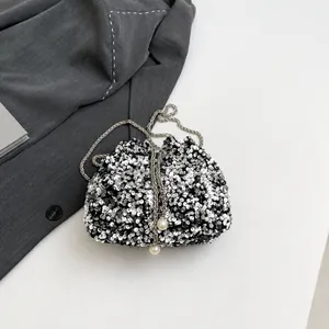 Dettaglio borsa a secchiello con paillettes, catena d'argento e perle sulla chiusura a coulisse