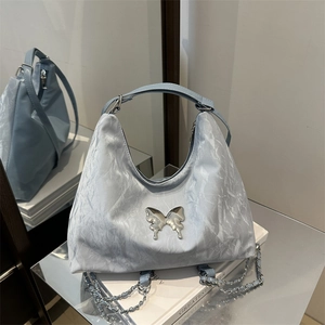 Light blue pleated shoulder bag with a silver butterfly charm and chain strap
