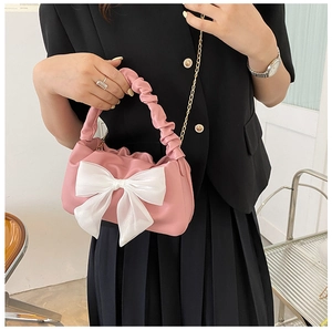 Detail of pink handbag with white mesh bow and golden chain strap on model outfit