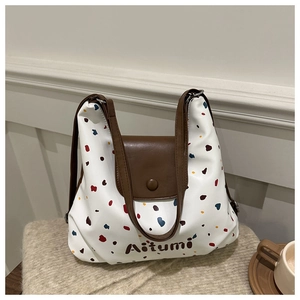 Dettaglio di una borsa tote bianca con pois colorati e finiture in pelle marrone