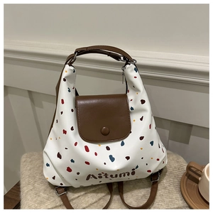 Dettaglio della borsa bianca a pois con patta in pelle marrone e chiusura magnetica