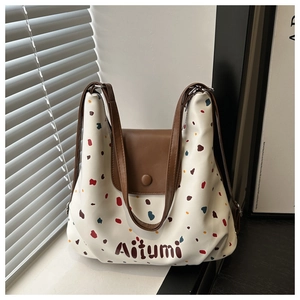 Dettaglio borsa shopper color crema con pois colorati e patta in pelle marrone pregiata
