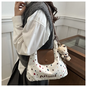 Dettaglio borsa shopper a pois con patta in pelle, logo e ciondolo gatto leopardato