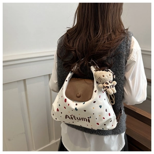 Dettaglio di una borsa tote bianca con pois colorati e ciondolo a forma di gattino