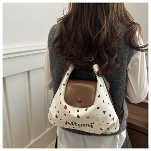 Dettaglio di una borsa tote in pelle bianca a pois con patta marrone e fibbia tonda