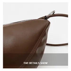 Detailed view of dark brown leather crescent bag showing precise stitching and silver hardware