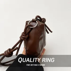 Close-up of the silver metal ring and decorative knot detail on the brown leather bag