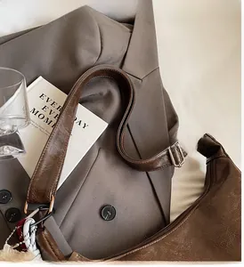 Detail of dark brown retro PU leather shoulder bag with gold metal hardware on grey blazer