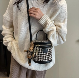 Houndstooth bucket bag with leather trim and plush bunny charm on shoulder strap