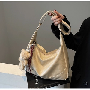 Detail of beige Hobo bag with smooth PU leather texture and cute teddy bear pendant