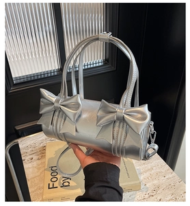 Detailed view of silver cylinder bag with large bows and metallic fashion texture
