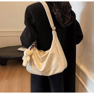 Detail of soft cream PU leather crossbody bag with brown plush bear charm accessory
