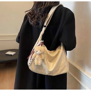 Detail of minimalist cream PU leather hobo bag with cute bear charm and striped strap