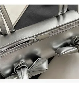 Detail of silver cylindrical bag showing smooth metallic zipper and leather texture
