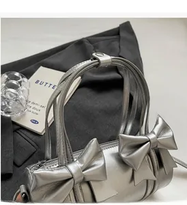 Close-up of a metallic silver cylinder bag with two large decorative bows on the surface