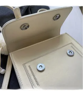 Detail of magnetic buckle closure on beige lychee pattern faux leather handbag