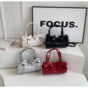 Multiple ballet-style cylinder bags in white, black, silver, and red with bow details