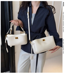 Detailed view of two minimalist white leather bags with golden clasps and adjustable straps
