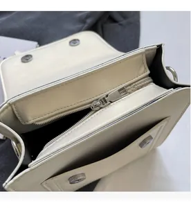 Detailed close-up of smooth metal zipper and premium cream leather interior of the bag