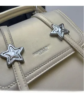 Detailed view of beige crossbody bag with silver star studs and embossed leather texture