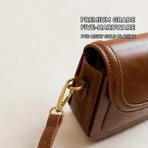 Detail of premium brown leather bag with glossy finish and polished golden hardware hooks