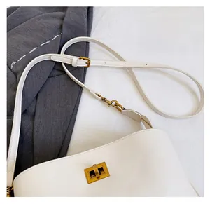 Detail of adjustable strap and vintage gold metal twist lock on white leather bag